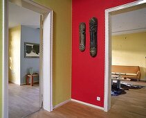 Wandgestaltung in tiefem rot + gelb, afrikanische Holzmasken an der Wand