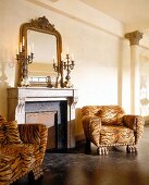 Zwei Leopardenfell-Sessel stehen vor dem Kamin (korinthische Säulen)
