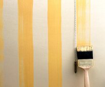 Cream coloured wall being painted with yellow stripes