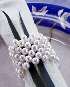 Ein Serviettenring aus Perlen und 2 Grashalme dekorieren eine Serviette
