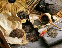 Diverse Teesorten auf getrockneten Blättern, Teekanne, Kandisstäbchen