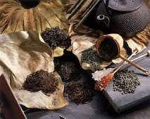 Diverse Teesorten auf getrockneten Blättern, Teekanne, Kandisstäbchen