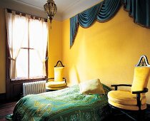 Schlafzimmer mit kräftig gelber Wand blauer Faltenbogen über dem Bett