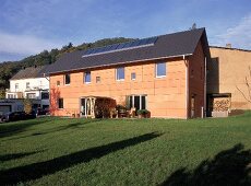 Doppelhaus mit apricotfarbenen Holzplatten und Solarkollektoren.