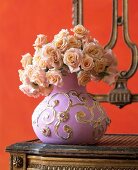 Close-up of baroque ornate vase with bouquet of roses in pastel on table