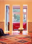 Blick durch einen Säulendurchgang auf rotes Sofa im Erker