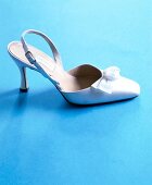 White elegant bridal shoes on blue background