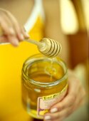 Close-up of honey dipper with jar of honey