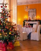 Room with decorated Christmas tree, lit candles and dining table