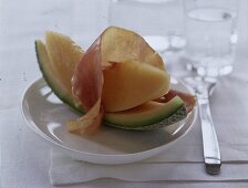 ein Stückchen frische Melone mit 1 Scheibe Parmaschinken
