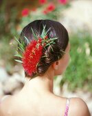 Frau hat ihr Haar hochgesteckt und mit einer roten Blüte festgesteckt