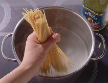Spaghetti zum Kochen in den Topf geben