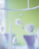 Close-up of white beads and small pompoms hanging with wire