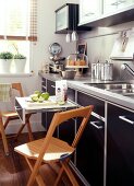 Space saving kitchen with drawer pull out table and wooden folding chairs