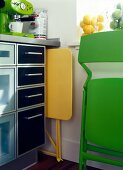 Space saving kitchen with yellow and green stowed folding chair and table