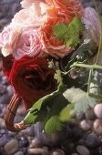Kleiner Rosenstrauss steht in einem Metallkännchen auf dem Pflaster