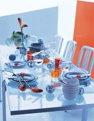Gedeckter Glastisch,blaues Geschirr, orangefarbene Gläser, Discokugeln