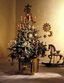 Christmas tree decorated with lit candles and sun and moon shaped Christmas ornaments