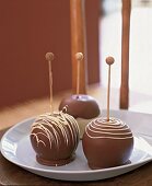 Drei Liebesäpfel m. Schokoladenüberzug auf weißem Teller