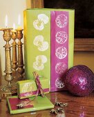 Neben Kerzen stehen 3 in grün und pink verpackte Geschenke