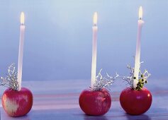 Mehrere Äpfel als Kerzenhalter, verziert mit Beeren und Gespenstergras