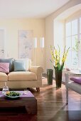 Teilansicht eines Raumes in hellen Farben: Sofa, Bodenvase m. Gladiolen