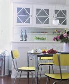 Blick in die Küche: gelbe Stühle im fifties-look + weißes Küchenbuffet