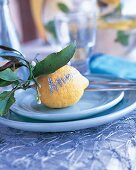 Tischkarte: Zitrone mit Namenszug auf türkisfarbenem Geschirr