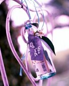 Close-up of bottle with purple love letter hanging on back of chair