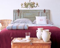 Tray and rustic bed with antique headboard and blankets in bedroom of farmhouse