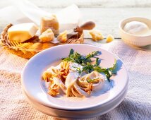 Spaghetti in cheese sauce garnished with rocket leaves and pine nuts on plate