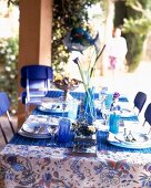 Table with blue table cloth, crockery, dishes and flower vase