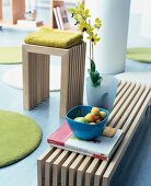 Close-up of stool and bench made of oakwood with flower vase and bowl of fruits on book