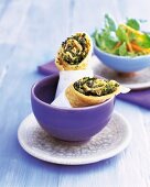 Kale rolls wrapped with tissue in a bowl with fresh salad