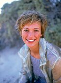 Portrait of pretty woman with short hair wearing jacket, smiling widely