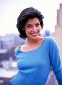 Portrait of pretty woman with dark short hair wearing blue top, smiling