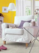 Sessel mit weißer Husse auf beigefarbenem Teppich, vor gelber Wand.