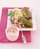 Lemon wedges, rosemary and vine leaves stuffed with vegetable on square plate