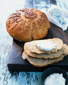 Round potato spelt bread with spices and cream cheese on wooden surface