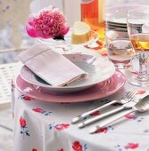 Ein weißer und ein rosa Teller auf einer geblümten Tischdecke