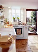 Bright kitchen with tiled floor, window and door to garden