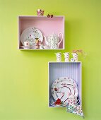 Shelf with porcelain crockery against green painted wall