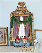 Pine garland decorated on mirror with lit candles in front