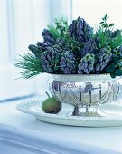 Pine twigs and hyacinths in silver vase on table