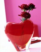 Red heart vase with roses on table