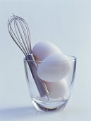 Three eggs and whisk in glass