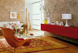 View of living room with oriental rug, rattan sofa and red wall cabinet