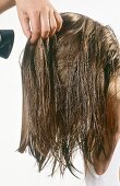 Woman with long layered wet hair getting her hair blow dried