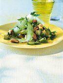 Mussel salad with avocado and cucumber on yellow plate with a glass of drink