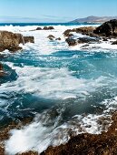 View of sea and sea foam along rocky coast